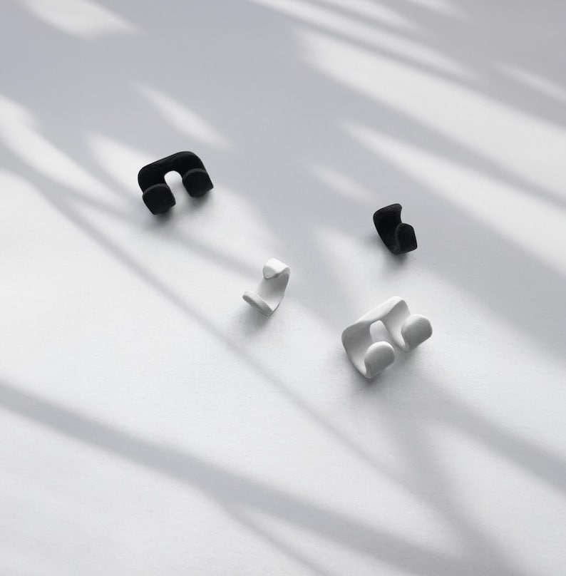Adjustable Earrings in black and white, double and single No-Pierced Conch Wraps on white surface with trendy shadowing