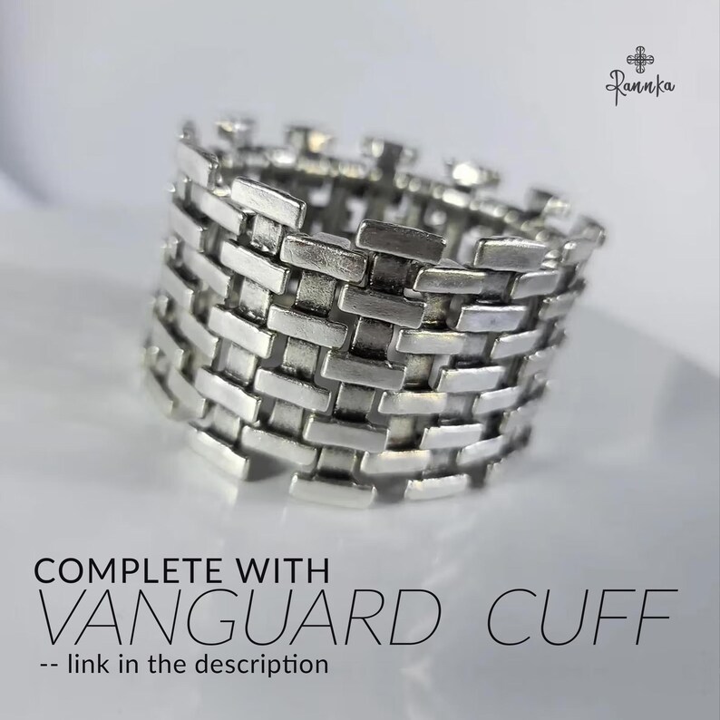 May include: A silver-colored ring with a woven brickwork design. The ring is wide and has a textured surface. Text on the image reads "COMPLETE WITH VANGUARD CUFF -- link in the description."