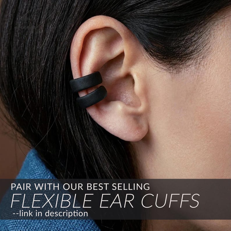 May include: A matte black double-band ear cuff worn on the upper cartilage. The image includes the text: PAIR WITH OUR BEST SELLING FLEXIBLE EAR CUFFS --link in description. The accessory features a smooth, solid finish and a simple, open-loop design.