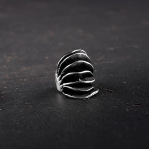 Avant-Garde  chunky silver ring for women on a black surface and background