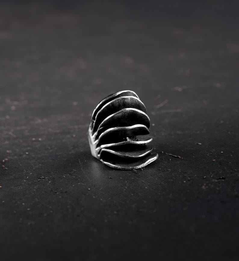 Avant-Garde  chunky silver ring for women on a black surface and background