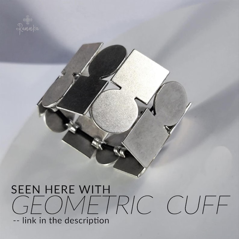 May include: Silver geometric cuff bracelet with a repeating pattern of shapes, including squares, circles, and rectangles. The bracelet is made of metal and has a flexible design. The text on the image says "SEEN HERE WITH GEOMETRIC CUFF -- link in the description."