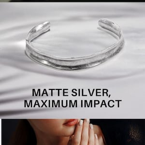 May include: Matte silver cuff bracelet. The image shows a close-up of a silver cuff bracelet with a textured surface. The bracelet is displayed on a person's arm and also on a white surface. The text "GIFT READY" and "MATTE SILVER, MAXIMUM IMPACT" are visible.