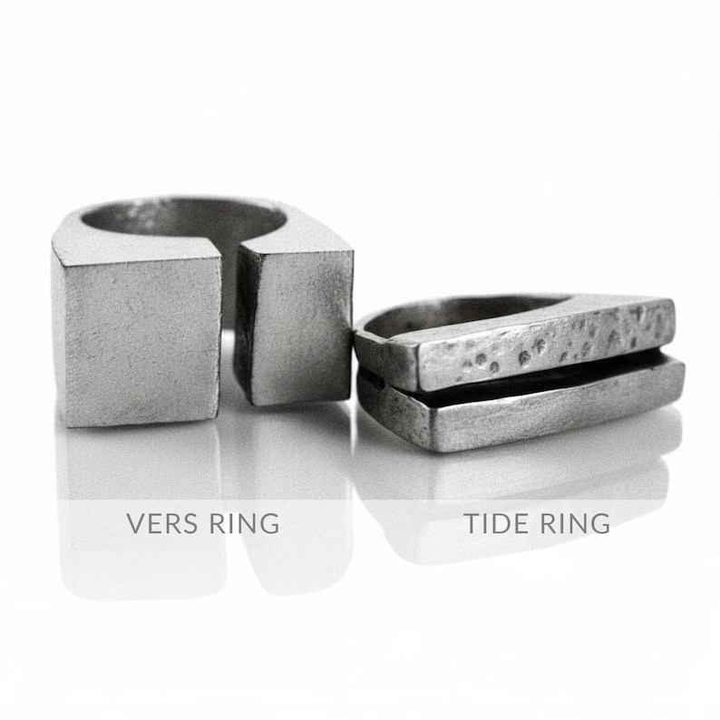 May include: Two silver rings, the "Vers Ring" is a square shape with a gap, and the "Tide Ring" is a layered, rectangular design. Both rings have a matte finish and are displayed on a reflective surface against a white background.