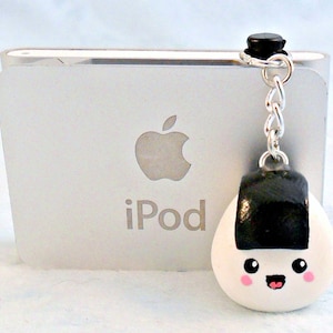 Pu&ograve; includere: Un ciondolo onigiri bianco e nero con un viso sorridente, attaccato a una catena d'argento e un ciondolo nero. Il ciondolo &egrave; appeso a un iPod.