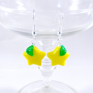 May include: A pair of yellow star-shaped earrings with green leaf accents hanging from silver hooks.