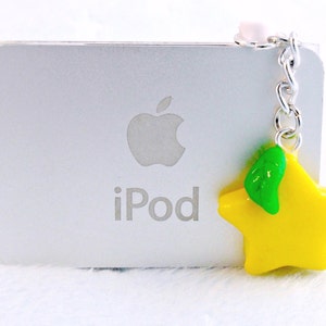 May include: A silver iPod with the Apple logo and the word "iPod" on the front. A yellow star charm with a green leaf is attached to the iPod with a silver chain.