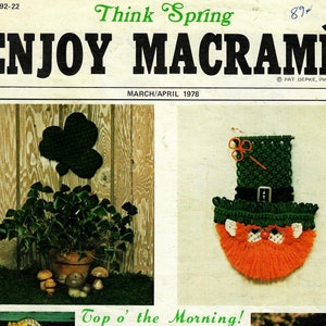 Op de afbeelding: Een tijdschriftcover met de titel "Enjoy Macrame" met een groene en oranje macramé-dwerg die aan een muur hangt. Het tijdschrift is van maart/april 1978 en bevat andere macramé-projecten, waaronder een klavertjevier, een globe, een tas en een bijenkorf.