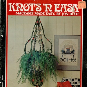 Puede incluir: Una portada de libro con el título "Knots'n Easy" y el subtítulo "Macrame Made Easy, by Jon Huot". La portada presenta un colgador de plantas de macramé con una planta de helecho verde colgando de él. El libro es el volumen uno de una serie sobre colgadores de plantas.
