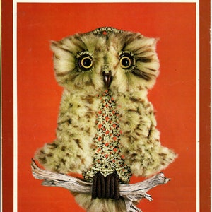 May include: A brown and white owl with large yellow eyes is perched on a branch. The owl is made of yarn and has a crocheted body. The owl is a craft project and is a great example of a handmade item.