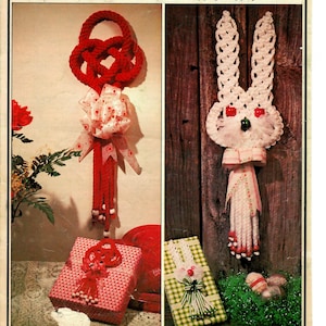 May include: Two crochet knot crafts, a red heart-shaped knot and a white bunny knot. The red knot is decorated with a white bow and beads. The bunny knot is decorated with a pink bow and beads. Both knots are displayed on a gift box.