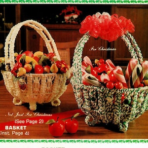 以下が含まれることがあります： 果物とキャンディーでいっぱいの白と緑の編み込みバスケットが2つ。バスケットには持ち手があり、3本の脚で立っています。バスケットの下には「Not Just For Christmas (See Page 2)」と「BASKET (Inst. Page 4)」の文字が印刷されています。緑のバスケットには「For Christmas」の文字が印刷されています。
