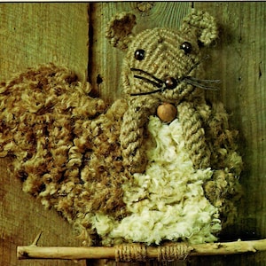 Może przedstawiać: Figurkę wiewiórki zrobioną z brązowego i białego sznurka z drewnianym noskiem. Wiewiórka siedzi na gałęzi.