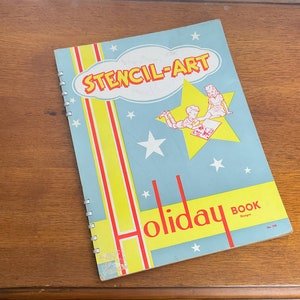May include: A blue and yellow book titled "Stencil-Art Holiday Book" with a drawing of two children on a star. The book has a spiral binding.