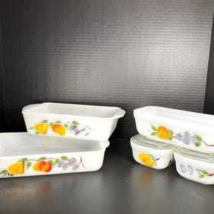 May include: Set of six white glass baking dishes with a fruit design. The dishes are in various sizes and shapes, including rectangular and square. The fruit design features pears, peaches, and grapes.