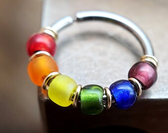 May include: A rainbow-colored beaded ring with a silver hoop. The beads are red, orange, yellow, green, blue, and purple.