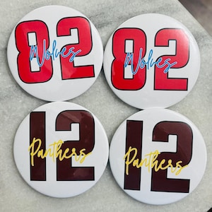May include: Four circular pin-back buttons with a white background. Two buttons feature the red number 82 with the word Wolves in blue script. Two buttons feature the dark maroon number 12 with the word Panthers in yellow script.