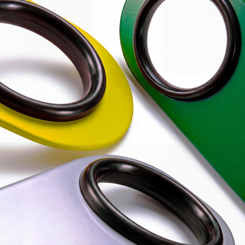 Black rubber spinner rings mounted on three colorful bottle openers, each a different color — arranged on a white background
