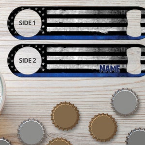 May include: A black and white American flag bottle opener with a blue stripe. The bottle opener has a cutout for opening bottles and the words "Side 1" and "Side 2" on each side. The bottle opener also has the word "NAME" printed on it.