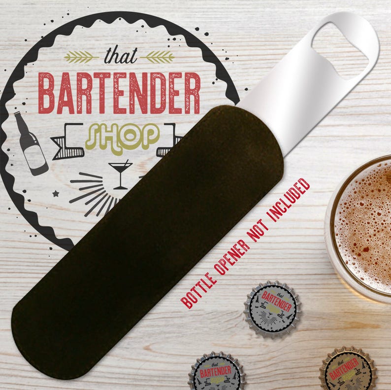 May include: A black and silver bottle opener with a white label that reads 'that bartender shop'. The bottle opener is on a wooden surface with three bottle caps that read 'that bartender shop'.