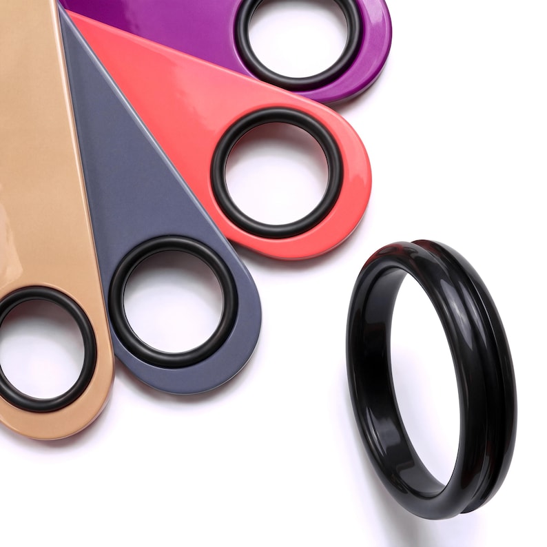 Black rubber spinner rings mounted on four colorful bottle openers, each a different color, and a larger black spinner ring on the side — arranged on a white background