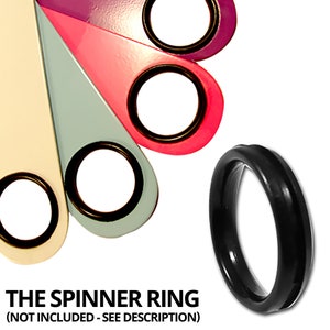 May include: Five colorful, teardrop-shaped pieces of plastic with a black ring in the center of each. The pieces are arranged in a semi-circle. The colors are purple, pink, light blue, cream, and black. The black ring is a spinner ring, and the text below the image reads 'THE SPINNER RING (NOT INCLUDED - SEE DESCRIPTION)'