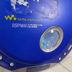 May include: A blue portable CD player with a circular design. The device features the Walkman logo, ESP MAX, and CD Walkman D-E350 CD-R/RW text printed on the top surface. It includes a small circular window, control buttons, and a blue open switch.