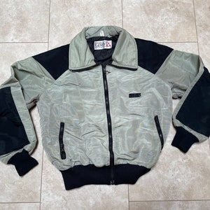 May include: A light green and black jacket with a zipper closure and a GERBER label. The jacket has a stand-up collar and two pockets on the front.