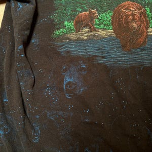 May include: Black long-sleeve shirt with a detailed graphic of bears in a forest setting. The design features a large bear in the center, with smaller bears and a body of water. The shirt has a starry night sky design.