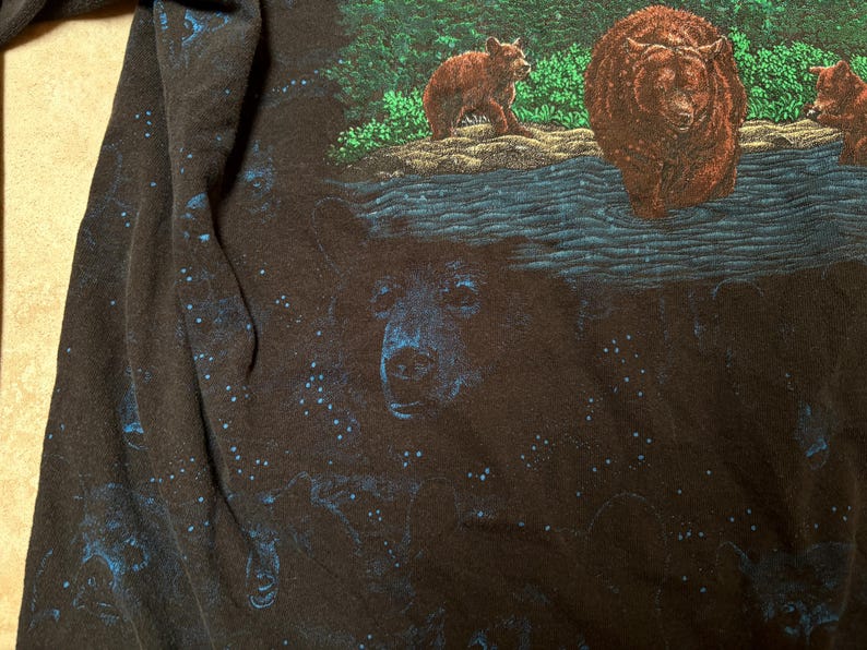 May include: Black long-sleeve shirt with a detailed graphic of bears in a forest setting. The design features a large bear in the center, with smaller bears and a body of water. The shirt has a starry night sky design.