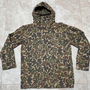Peut inclure: Une veste à capuche camouflage avec plusieurs poches. La veste est faite d'un tissu épais et résistant et possède une capuche à cordon.