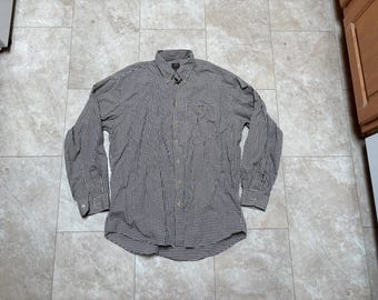 May include: A long-sleeved button-down shirt with a black and white checkered pattern. The shirt has a collar, a chest pocket, and buttoned cuffs. The shirt is made of a lightweight fabric and is suitable for casual wear.