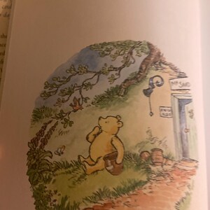 Pode incluir: Uma ilustra&ccedil;&atilde;o em aquarela do Winnie the Pooh sentado em um caminho em uma floresta. Ele est&aacute; segurando uma panela em sua m&atilde;o e olhando para cima para uma &aacute;rvore. A ilustra&ccedil;&atilde;o est&aacute; em uma moldura circular com um fundo azul claro.