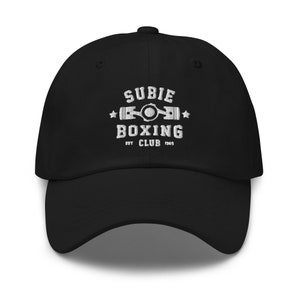 Peut inclure: Casquette de baseball noire avec un texte brodé en blanc qui dit "SUBIE BOXING CLUB EST 1969" et une image stylisée d'un piston.