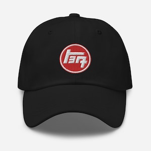May include: A black baseball cap with a red circle and white embroidered Toyota logo. The logo is the Japanese characters for "Toyota" in a stylized font.