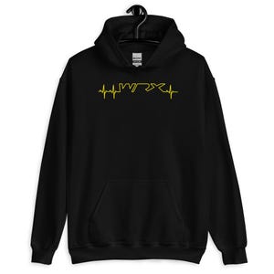 Puede incluir: Sudadera con capucha negra con un gráfico amarillo de un latido del corazón con las letras WRX en su interior.