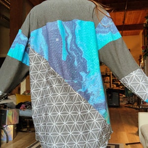 May include: A long-sleeved shirt with a geometric pattern on the bottom half and a blue and green abstract design on the top half.