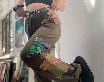 May include: Green cargo pants with colorful patchwork details. The pants have a drawstring waist and a relaxed fit.