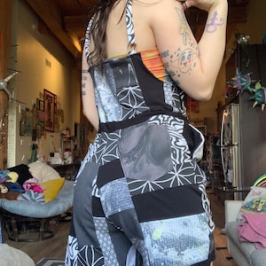 Puede incluir: Pantalón vaquero de parches negro y blanco con un patrón geométrico. El pantalón tiene un bolsillo grande en la espalda y está hecho de una variedad de telas.