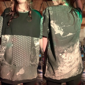 May include: A black and white graphic tee shirt with a geometric pattern and abstract design. The shirt has a relaxed fit and a crew neck.