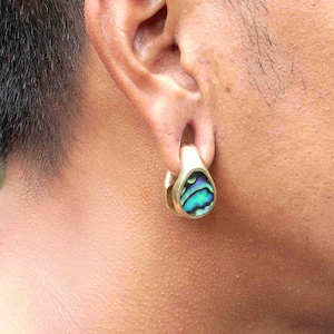 Op de afbeelding: Een gouden oorplug met een inleg van blauwe, groene en paarse abalone-schelp.