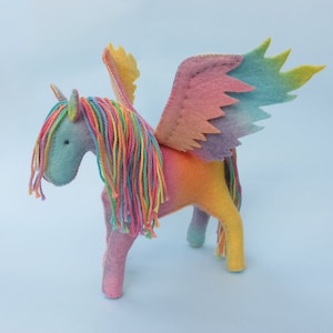 May include: A rainbow-colored felt unicorn with wings. The unicorn has a long, flowing mane and tail made of yarn. The wings are also made of felt and are iridescent.