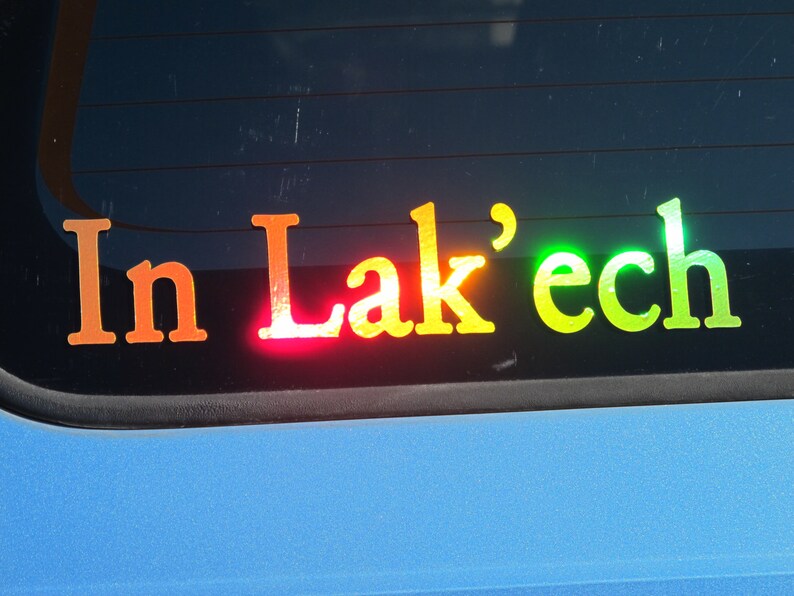 May include: A rainbow-colored sticker on a car window that reads "In Lak'ech".