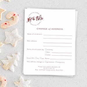 Puede incluir: Una pila de formularios de papel blanco con el texto "North Pole Official Form" y "Change of Address" en color burdeos. El formulario incluye secciones para rellenar con el nombre de un niño y la nueva dirección. Galletas navideñas, incluyendo estrellas y un bastón de caramelo, están esparcidas alrededor de los formularios.