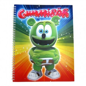 Op de afbeelding: Een groen gummibere karakter met blauwe ogen en een grote glimlach op een kleurrijk notitieboek met het woord "Gummibär" in rode letters.