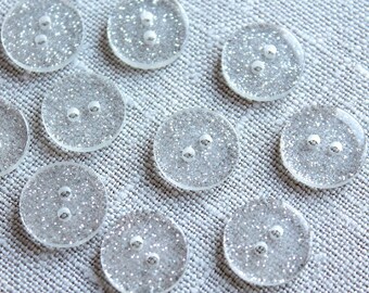 May include: A collection of clear, round buttons with a sparkly, silver glitter finish. Each button has two holes.