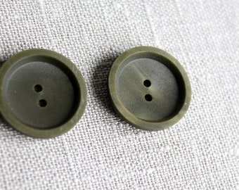 May include: Two dark green plastic buttons with two holes each.