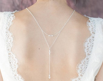 May include: A silver back necklace with a delicate chain and small crystal accents. The necklace has a long, dangling drop with a larger crystal at the end.