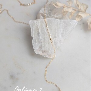 May include: A delicate gold chain necklace with a single pearl pendant. The necklace features a row of small glass pearls along the chain. Option 2: Glass Pearls (shown in Ivory)