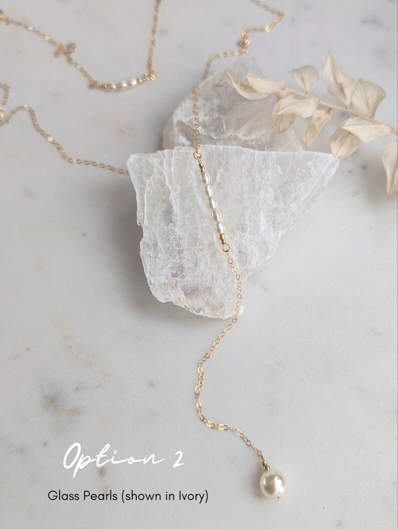 May include: A delicate gold chain necklace with a single pearl pendant. The necklace features a row of small glass pearls along the chain. Option 2: Glass Pearls (shown in Ivory)